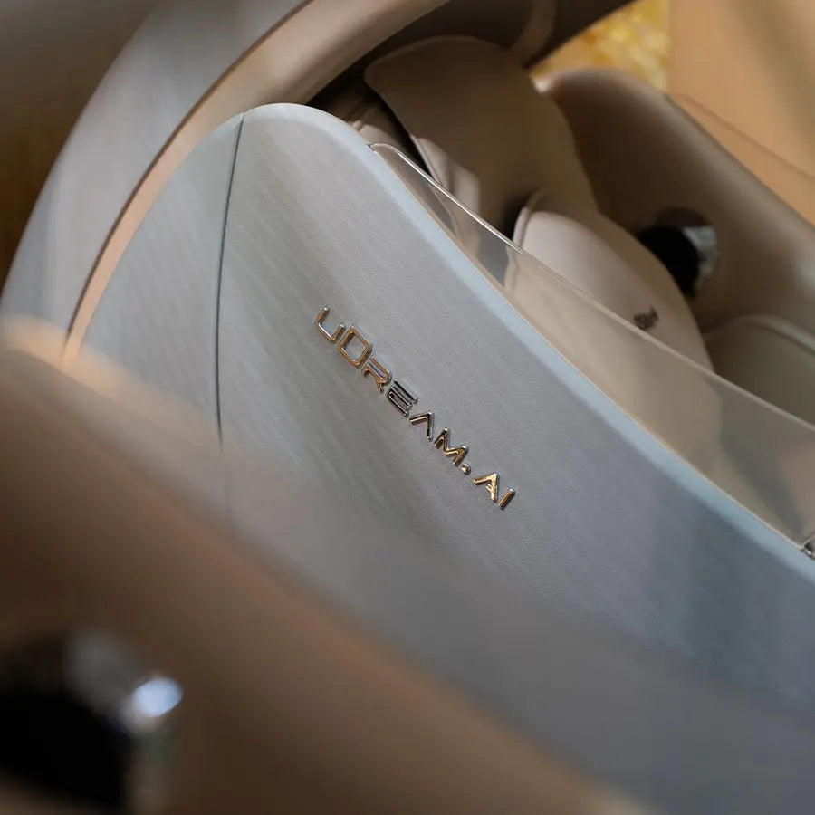Close-up of a metallic brushed silver panel with the gold 'uDream.AI' logo, set against a luxurious beige interior background.