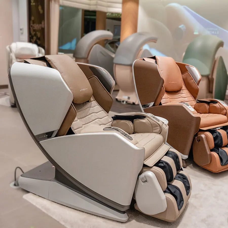 A modern massage chair in cream and taupe leather is shown in a showroom, with several similar chairs in different colors lined up behind it.